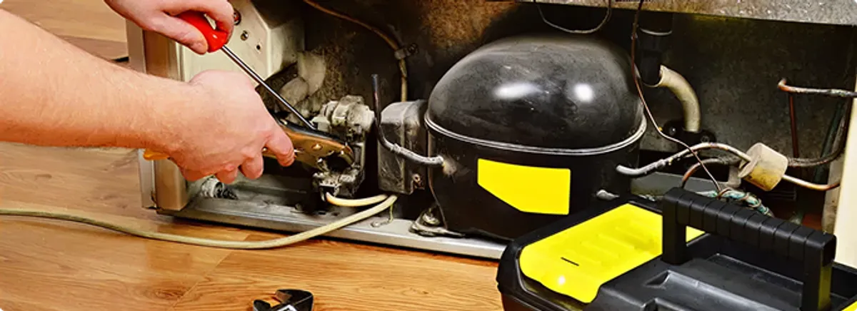 Refrigerator repair technician fixing the compressor and wiring in Hartsburg, MO