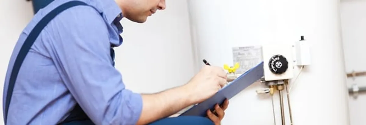 Water heater repair technician inspecting the unit and recording service notes in Columbia, MO